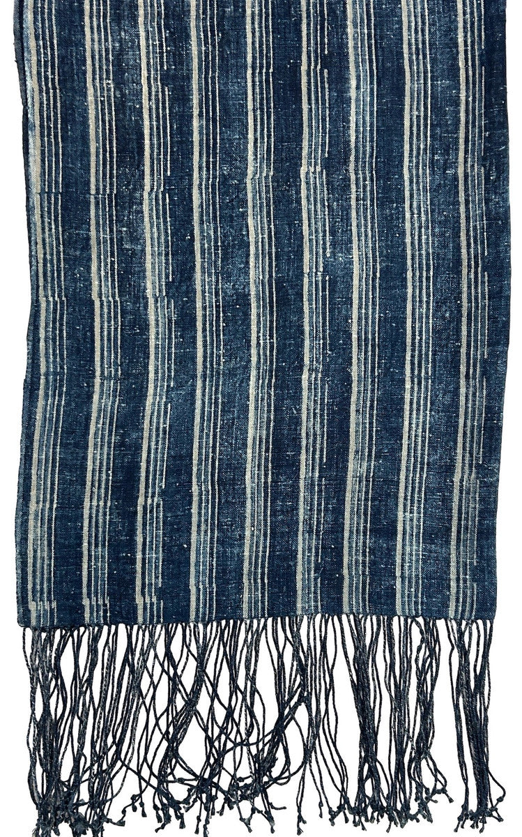 quarter view Handwoven indigo dyed linen throw. This lush throw has a beautiful striped indigo pattern that was dyed in an 'abrash' method. The back side is solid dark indigo. This is a heavy linen throw that would be beautiful on the end of a bed or on the couch. 