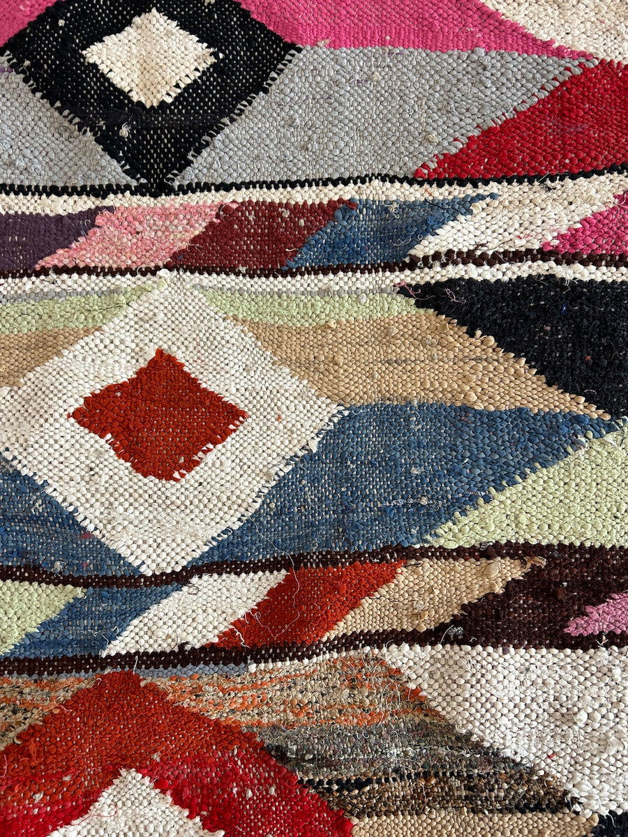 detail. Handwoven rag rug with a dynamic diamond and pattern from weavers in southern Morocco. Beautiful on the floor or on the wall. A medley of colors. Short tied fringe at one end. Size: Approx. 34" x 76"